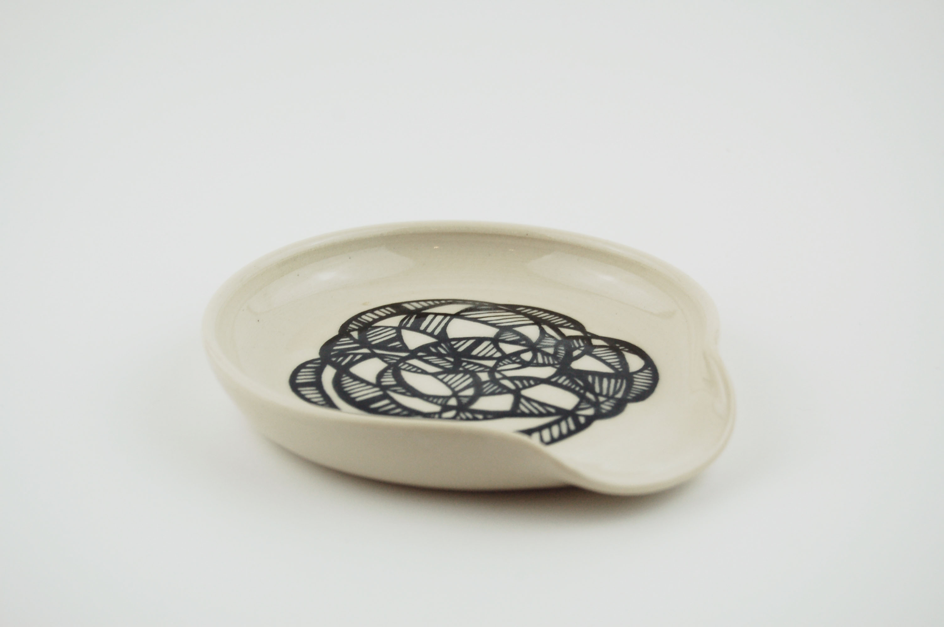 Ceramic spoon rest with black lines on off-white clay